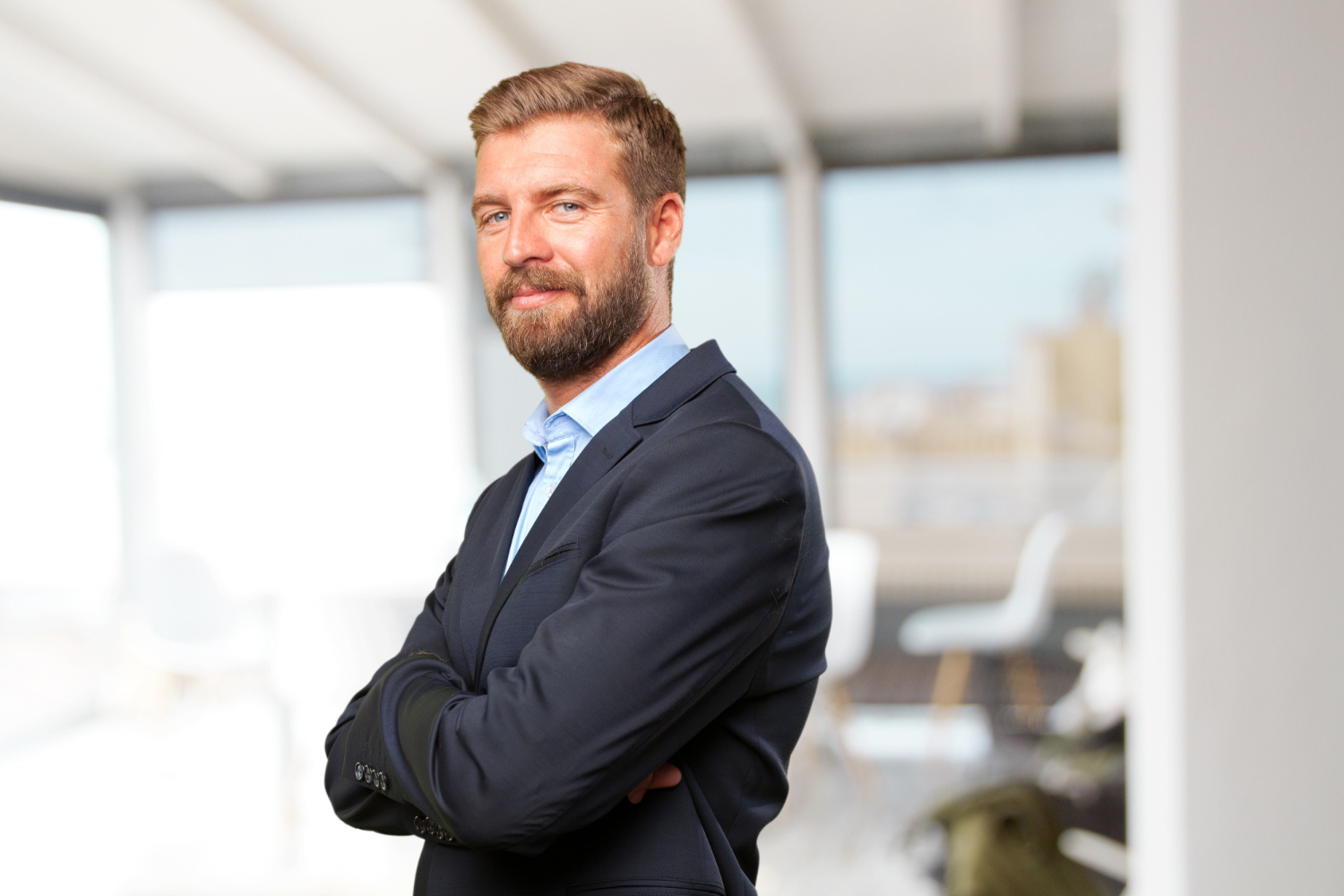 A portrait of a confident businessman in a dark suit smiling slightly.