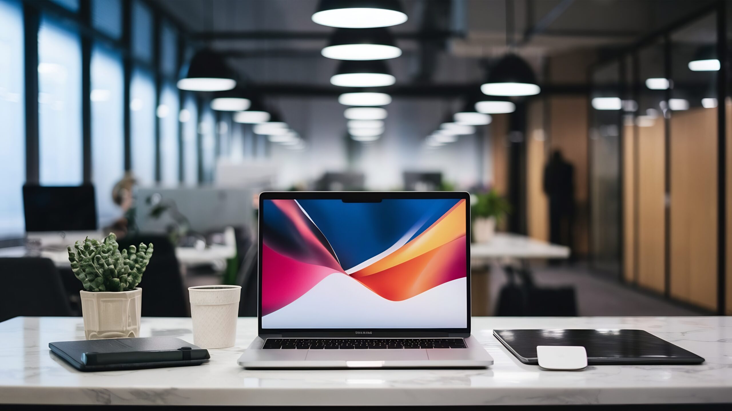A laptop screen displaying a colorful graphic on a clean desk with a blurred office background.